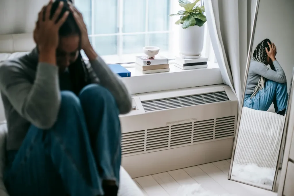 Person sitter stilla med handen mot pannan i lugn miljö, symboliserar känslan av att vara trött mentalt men inte fysiskt